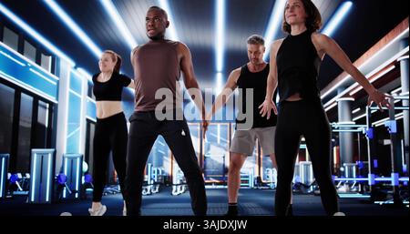 Young African American Man Lifting Weights In Diverse Group Training Session. Fitness Instructor Coaching Diverse Team Stock Photo