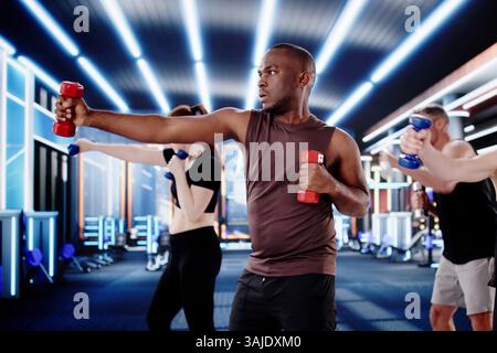 Dynamic Fitness Trainer Leads Multiracial Group To Exercise During Boxing Session. Stock Photo