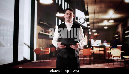 Success In The Cafe: Latino Owner Using Tablet To Plan. Stock Photo