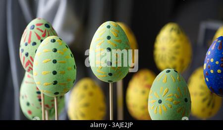 A collection of beautifully decorated Easter eggs on sticks, with vibrant colors and creative designs on display, ready for the holiday. Stock Photo