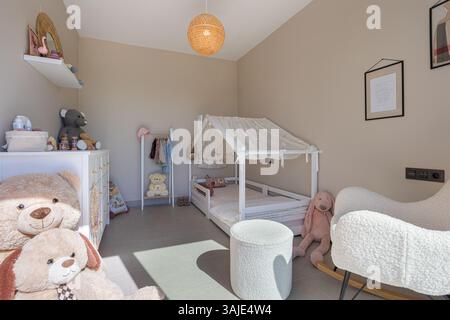 Delightful child’s bedroom featuring a cozy house-frame bed and plush stuffed animals. Stock Photo