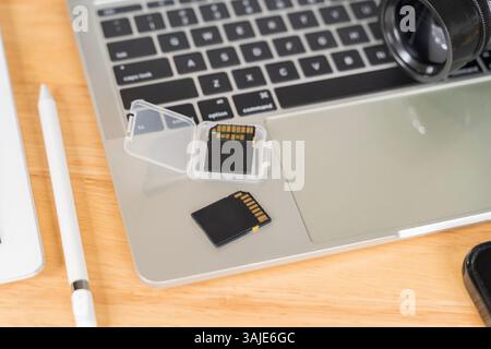 Laptop, external hard drive, modern digital camera with flip screen, two sd memory cards and lens on gray background. Photographer's equipment. Top vi Stock Photo
