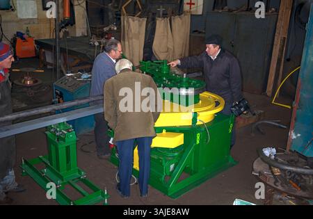 The workers and engineer discuss with boss testing of new machine for pipe bending at the Ukrainian plant. Stock Photo
