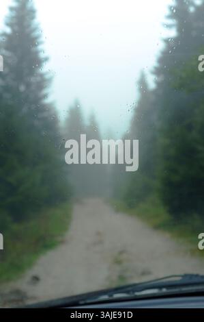 raindrops on the windshield of a car, in the blurred background an autumn forest on a country road in Ravna Romanija, Bosnia And Herzegovina Stock Photo