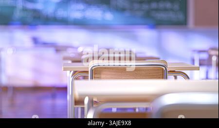 Empty classroom with wooden school desks and chalkboard in the background 3d Stock Photo