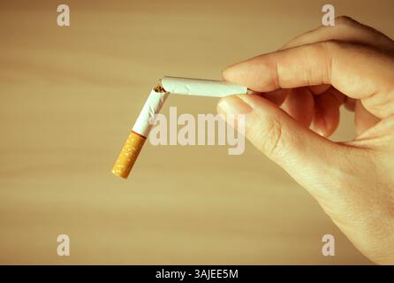 Toned Photo of Person hold a Broken Cigarette on a Table Background closeup Stock Photo