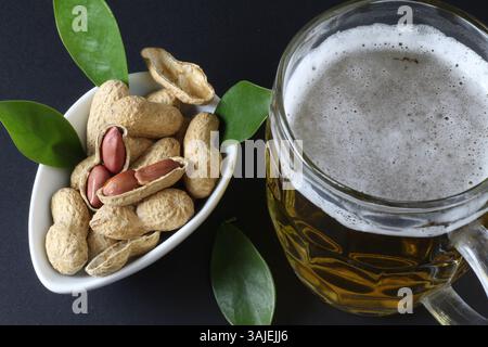Mug of beer and peanuts in shell on table Stock Photo