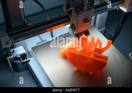 3D Printer Creating Vibrant Orange Prototype Model Stock Photo