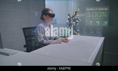 Female Professional Uses Augmented Reality Headset to Visualize 3D Hologram of Molecular Compounds in Advanced Office. Virtual Visualization of Artificial Intelligence Based Software Interface. Stock Photo