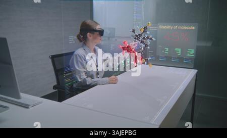 Female Professional Uses Augmented Reality Headset to Visualize 3D Hologram of Molecular Compounds in Advanced Office. Virtual Visualization of Artificial Intelligence Based Software Interface. Stock Photo
