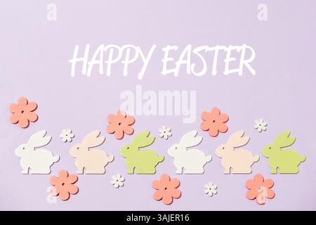 Colorful Easter bunny decoration with a purple background. The bunny decorations are arranged in a row and there are flowers in the background. The me Stock Photo