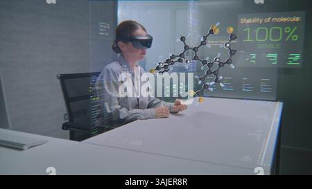 Female Professional Uses Augmented Reality Headset to Visualize 3D Hologram of Molecular Compounds in Advanced Office. Virtual Visualization of Artificial Intelligence Based Software Interface. Stock Photo
