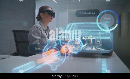 Futuristic Office: Female Automotive Professional Wearing Headset Uses Virtual Reality Hologram to Construct 3D Prototype of High-Tech Electric Car on Li-Ion Battery. Advanced Artificial Intelligence. Stock Photo