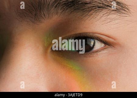 Eye close-up with colorful prism light reflection on skin Stock Photo