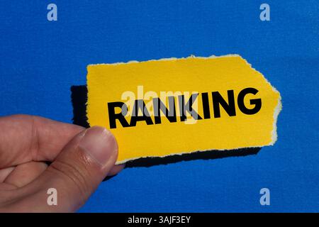 Ranking message written on ripped torn yellow paper piece on blue background. Conceptual ranking symbol. Copy space. Stock Photo