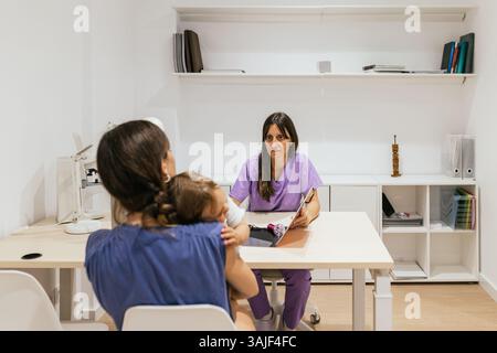 Optometrist talking with mother holding her baby daughter Stock Photo