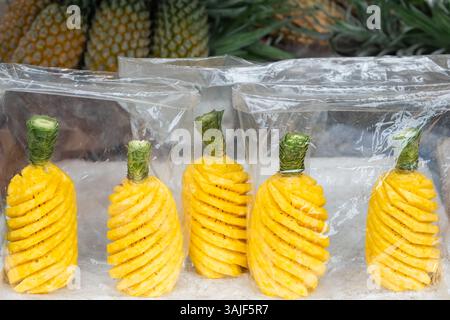 Ripe pineapple peeled in plastic bag selling in local market. Whole ripe pineapple peeled. Nobody, street photo. Delicious peeled pineapples in plasti Stock Photo