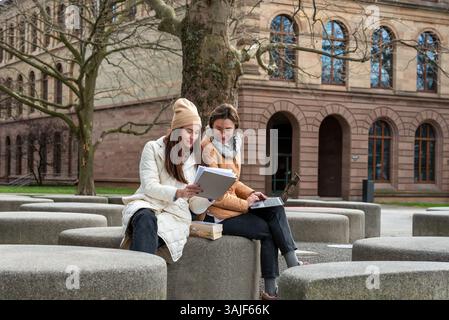 Well-dressed students collaborate with laptops and books in a tranquil University Park Stock Photo