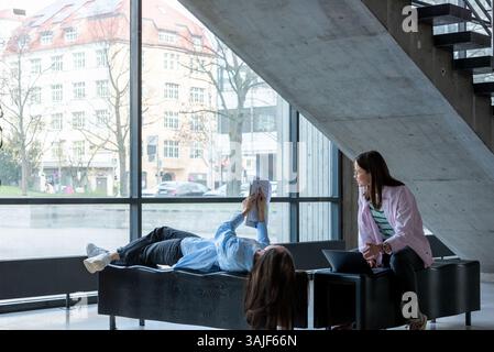 University students work together, blending technology and books in a cozy study spot. Stock Photo