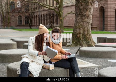 Well-dressed students collaborate with laptops and books in a tranquil University Park Stock Photo