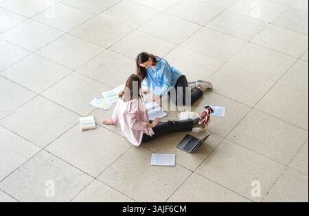 High angle view with two female students sitting on the floor and studying for the exams. Stock Photo