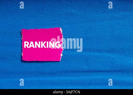 Ranking message written on ripped torn pink paper on blue background. Conceptual ranking symbol. Copy space. Stock Photo