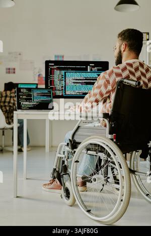 Vertical shot of unrecognizable IT specialist with disability coding on compute at his workplace in modern office Stock Photo