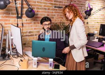 Colleagues collaborating on laptop in modern office Stock Photo