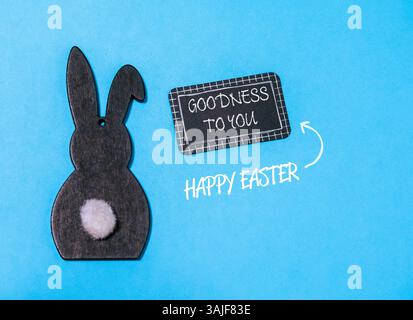 Rabbit is sitting on a blue background with a sign that says Goodness to you above it Stock Photo