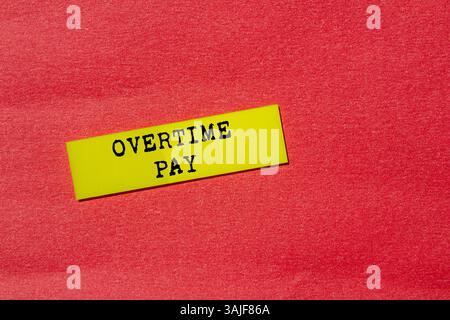 Overtime pay message written on yellow paper label on red background. Conceptual overtime pay symbol. Copy space. Stock Photo