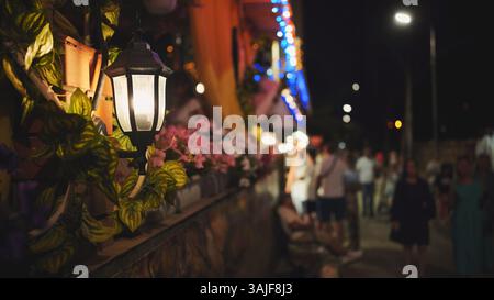 Warm street lamp casting golden glow over blurred nighttime silhouettes along black sea promenade in crimea Stock Photo