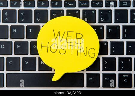 Yellow speech bubble on top of laptop keyboard with text WEB HOSTING. Business and technology concept. Stock Photo
