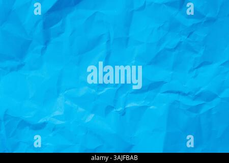 A close-up, top-down shot reveals the textured surface of crumpled light blue paper. Background concept. Stock Photo