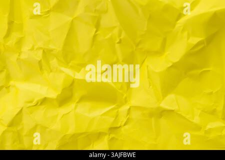 A close-up, top-down shot showcases the crinkled and uneven texture of yellow paper. Background concept. Stock Photo