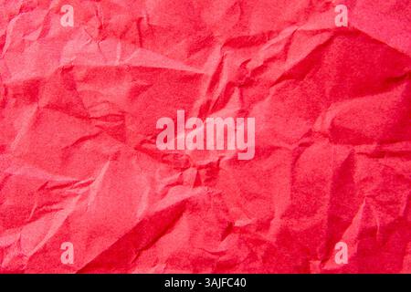 A close-up, top-down shot showcases the crinkled and uneven texture of bright red paper. Background concept. Stock Photo