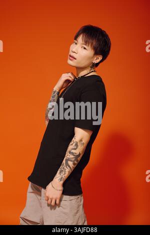 A stylish young Asian man adjusts his dress shirt, showing off ...