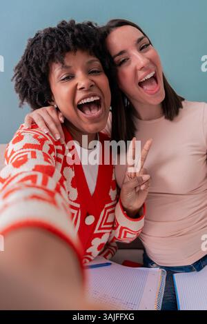 Two happy women taking a fun selfie together while sitting on a couch at home Stock Photo