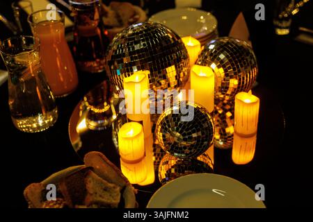 A candlelit table featuring reflective disco balls and flickering candles creates a warm and inviting ambiance for dining or celebration. Stock Photo