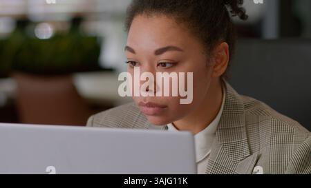 Serious ethnic woman African American girl businesswoman female employer broker agent lady business worker manager look at laptop pc screen work Stock Photo
