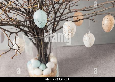 Easter tree decorated colorful pastel white and beige eggs. Birch branches with hang eggs in vase. Happy Easter greeting card. Close up Stock Photo