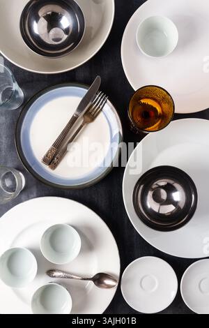 Top view of an empty plates, bowls, glasses and cutlery placed on a black chalkboard background. Flat lay. Top view. Food concept. Stock Photo