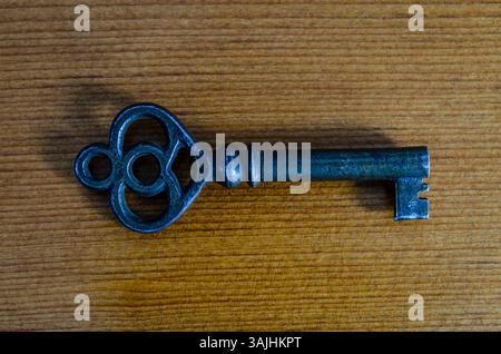 Antique Blue Skeleton Key on Woodgrain Background, shown at a side view macro closeup Stock Photo
