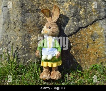Easter bunny in the grass in front of a large ston Stock Photo