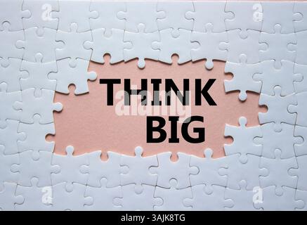 Think big symbol. White puzzle with words Think big. Beautiful pink background. Business and Think big concept. Copy space. Stock Photo