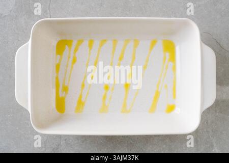 White rectangular baking dish with olive oil drizzled in vertical lines. Stock Photo
