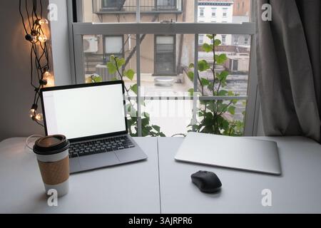 Modern home office setup with laptops, a cup of coffee, and comfortable workspace for remote work or freelancing, featuring a clean desktop and a cozy Stock Photo