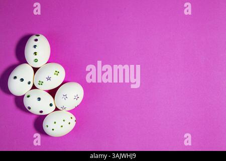 Top View of Sparkling White Easter Eggs on Purple. Flat lay composition showing sparkling Easter eggs on orange background, representing joy, festivit Stock Photo