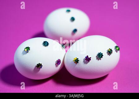 Eye-catching Easter concept with shiny decorations placed on eggs and contrasted against a vivid pink background. Stock Photo