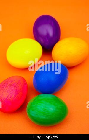 Easter Flat Lay with Multicolor Eggs in Rustic Bowl Isolated On Orange. Top view photo of festive colored eggs placed inside a textured bowl with deco Stock Photo