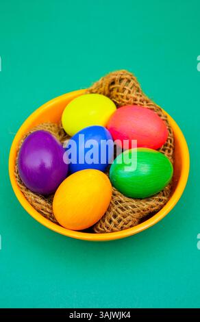 Multiple dyed eggs placed in a simple bowl with thread details on Orange background, giving a natural yet festive spring feel. Stock Photo